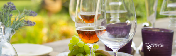 Gefüllte Weingläser mit Roséwein stehend auf einem Gartentisch im Freien